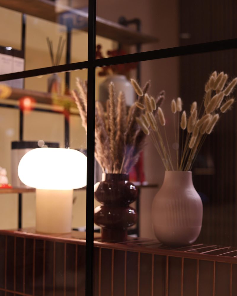 Glowing table lamp and dried-flower vases in the shopfront window at One Degree Edit, Havelock 2
