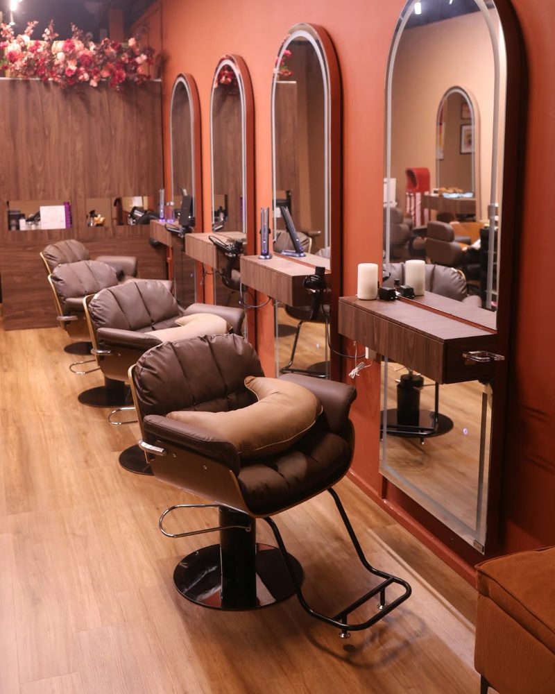 Row of styling chairs beneath arched brass mirrors against terracotta walls at One Degree Edit, Havelock 2